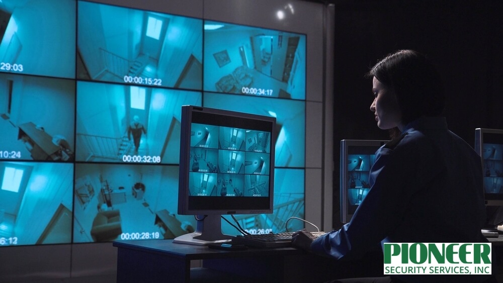 Female security operator actively performing live video monitoring from a control room, watching multiple CCTV feeds including night vision surveillance footage.