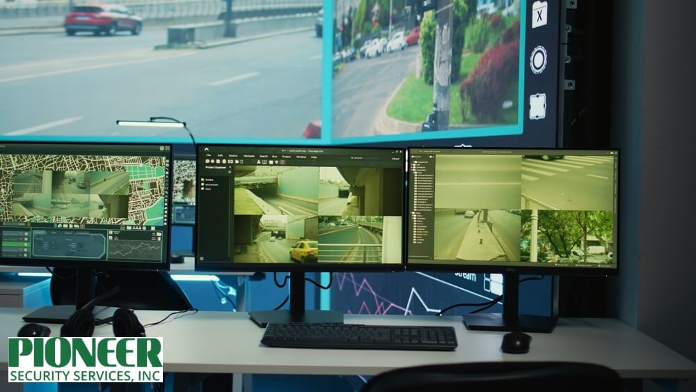 Live-Video-Monitoring-Traffic-Control-Screens.tock_2496197879 Empty control room desk with three monitors displaying live video monitoring of city streets, traffic cameras, and a map-based surveillance interface.